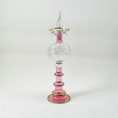 A delicate pink and clear glass bottle jewelry ornament with gold accents for bedroom decor featuring a twisted stopper