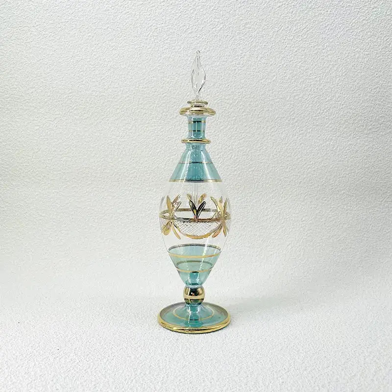 A tall elegant light blue glass bottle with gold leaf detailing used as glass bottle jewelry ornaments