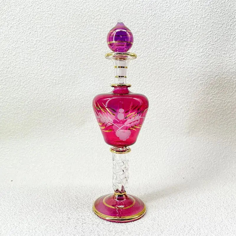 A vibrant fuchsia glass bottle jewelry ornament with gold accents and etched floral design for bedroom decor