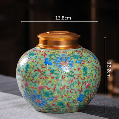 Ornate floral ceramic storage jar with gold-toned lid featuring blue pink and yellow patterns on light green glaze
