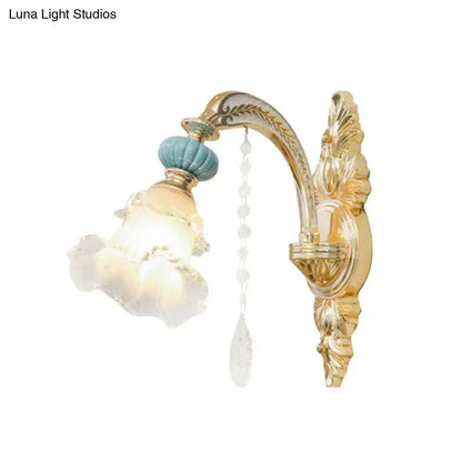 Ornate gold and blue glass wall mount light with teal ceramic finial and crystal beads for bedroom illumination