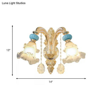 Ornate gold wall mount light with two fluted blue glass shades accented by turquoise ceramic finials and crystal pendants