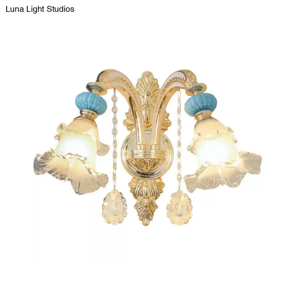 Ornate gold wall mount light with blue glass shades, turquoise ceramic finials, and crystal pendant accents for bedroom