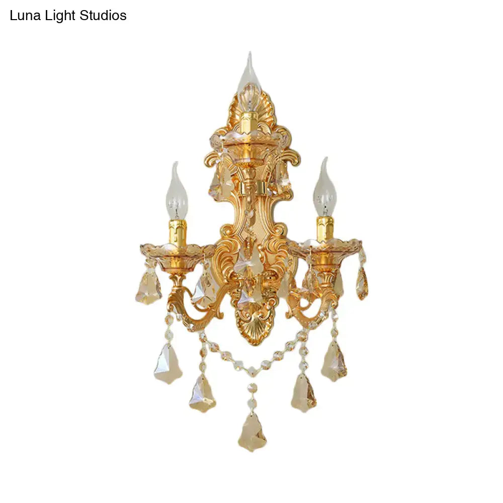 Ornate gold metal fixture living room sconce with crystal accents and dangling teardrop crystals in a 3 inch fixture