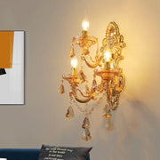 Ornate gold metal fixture living room sconce with three lit candle-style bulbs crystal droplets and dangling beads inch fixture