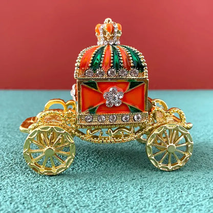 Ornate gold enamel crown jewelry box shaped as a carriage with red and green enamel and rhinestone accents