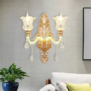 Ornate gold floral wall lamp with two frosted glass tulip shades and clear crystal glass teardrop accents for bedroom use