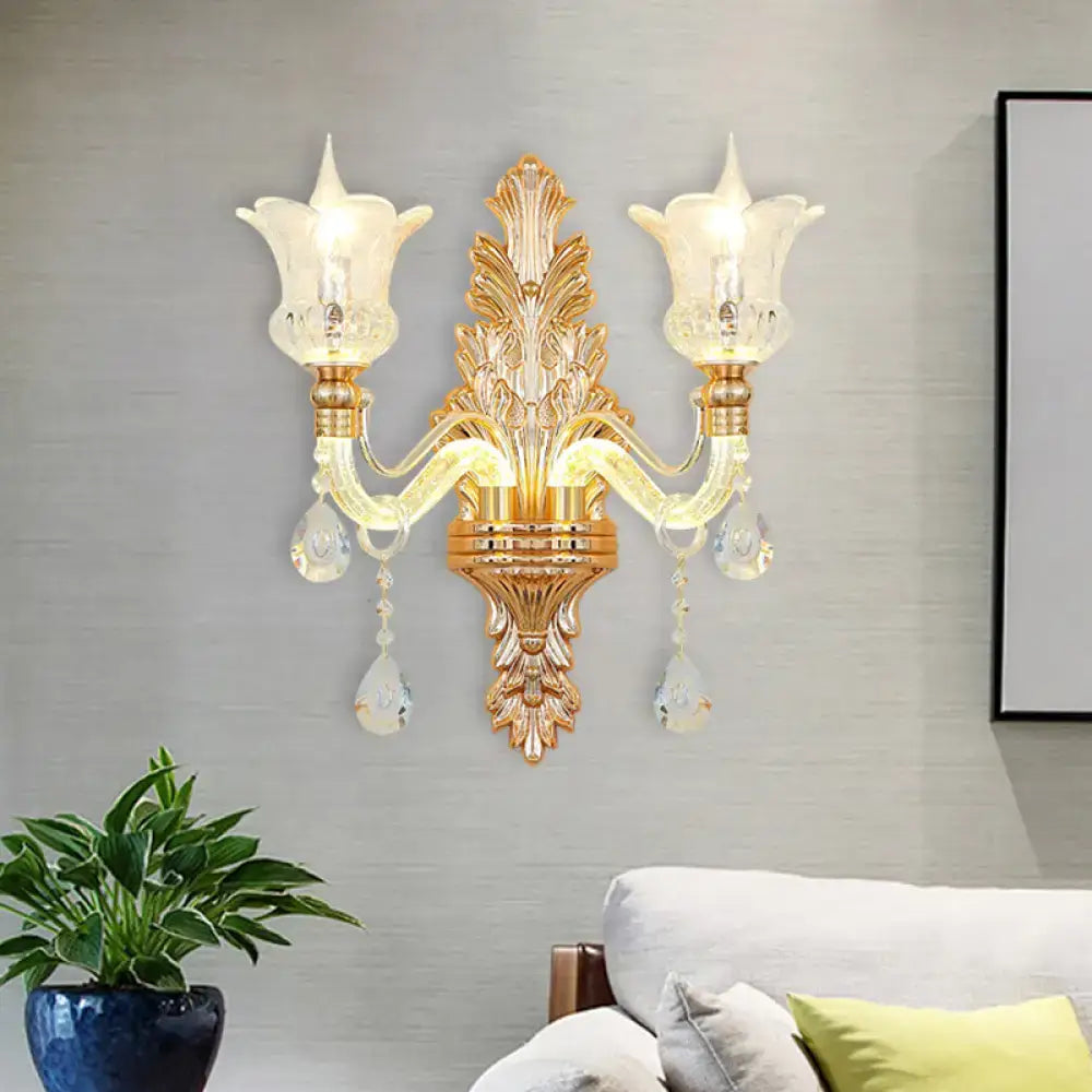 Ornate gold floral wall lamp with two frosted glass tulip shades and clear crystal glass teardrop accents for bedroom use