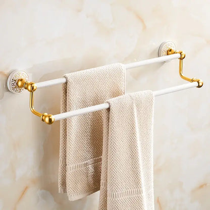 Ornate gold and white double towel rack with floral wall-mounted brackets holding beige textured towels from decorbites bathroom accessories set