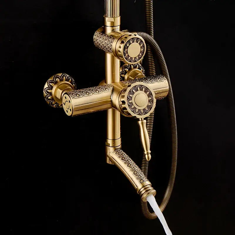 Ornate gold-colored brass shower faucet set with floral engraving and matching handheld for bathroom use