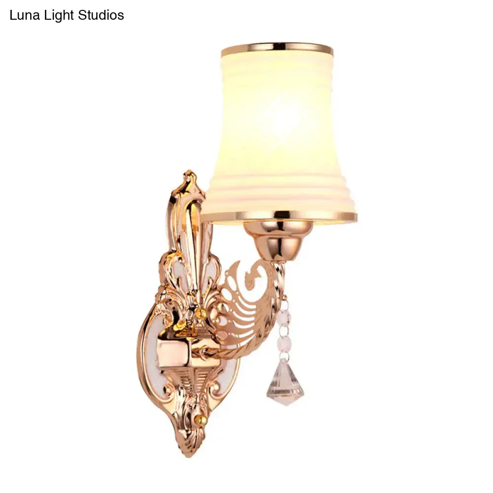 Ornate gold-toned tapered bell wall sconce with frosted opal glass tapered shade and crystal accents for bedroom lighting