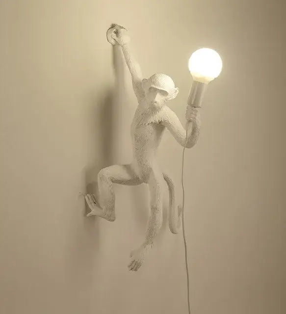 Ornate white monkeys pendant chandelier with textured monkey wall lamp holding glowing bulb for living room decor