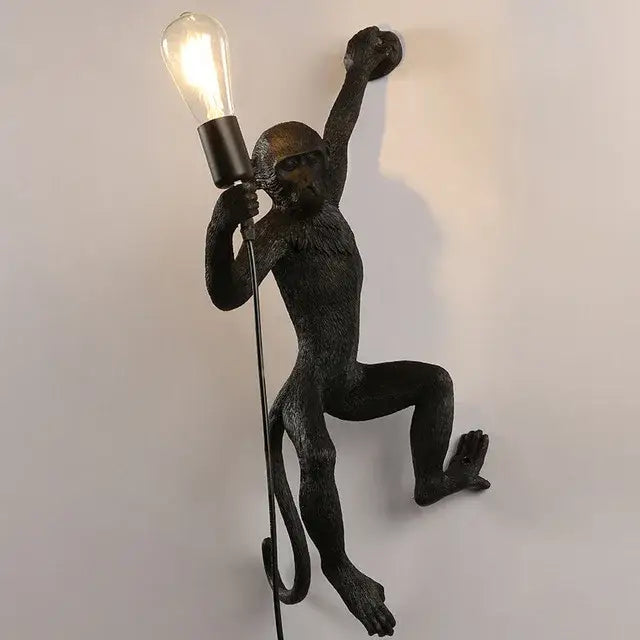 Black monkey wall lamp with textured matte finish holding exposed Edison bulb for ornate white monkeys pendant chandelier