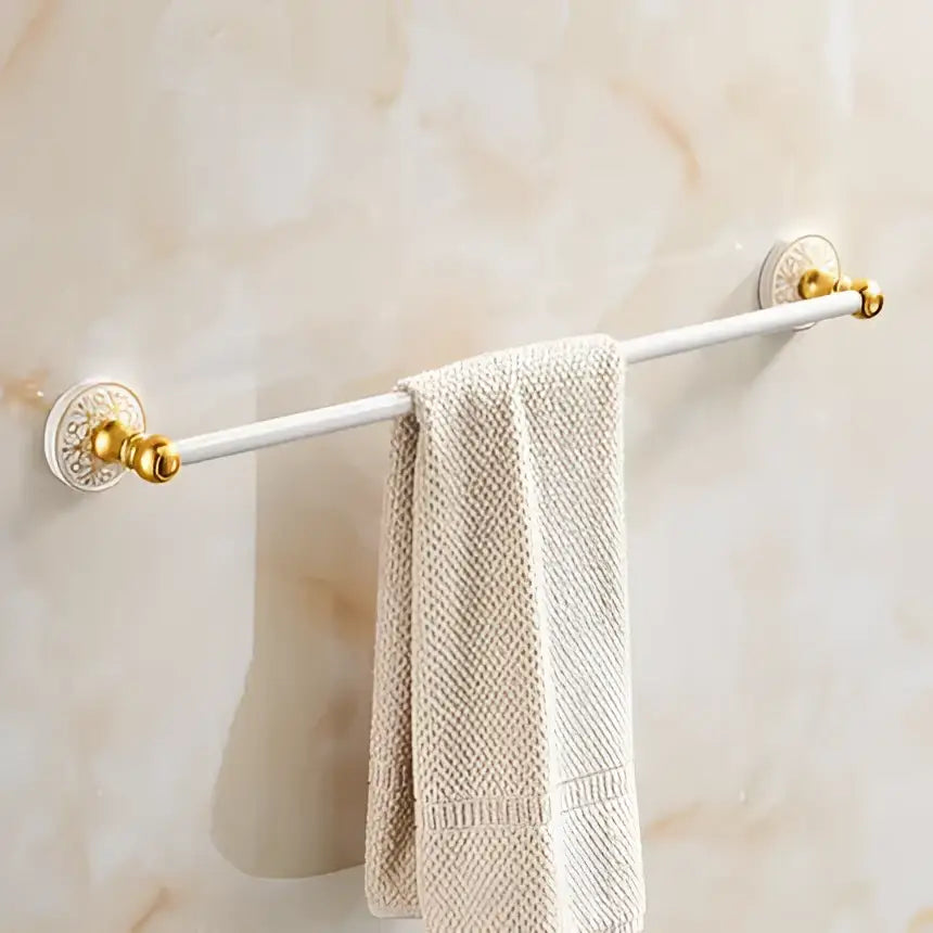 Ornate white and gold bath hardware set with gold-toned towel rack and beige textured towel by decorbites bath hardware
