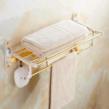 Gold-toned towel rack with white ornate brackets holding beige towel and white washcloth from decorbites bath hardware set