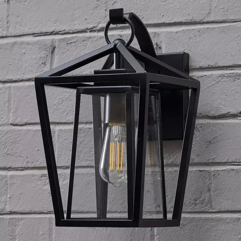 Black wrought iron outdoor wall light with clear glass shades and visible filament bulb by DecorBites