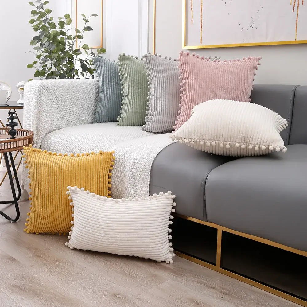 Set of pastel corduroy pompom cushion covers with colorful pom-pom trim for living room decor on gray sofa