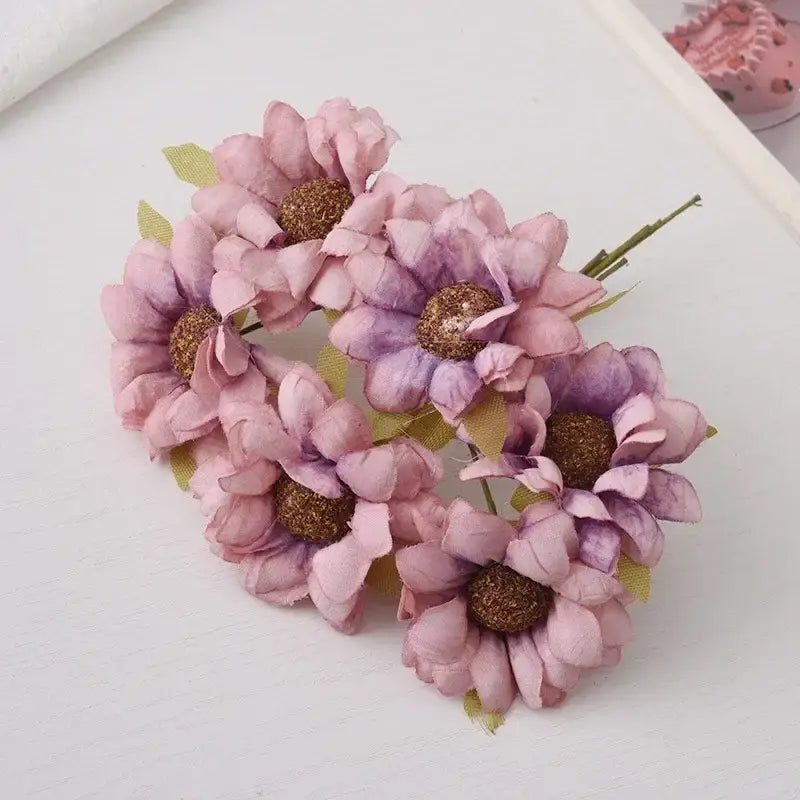 A pastel decorbites daisy sunflower bouquet featuring delicate pink and purple paper flowers with glittery brown centers for wedding room decor