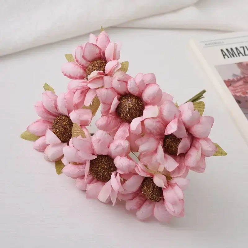 A pastel decorbites daisy sunflower bouquet featuring delicate pink artificial flowers with brown centers and green leaves for wedding room decor