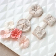 Set of delicate pastel-colored silicone five petals flower molds with intricate petal designs and matching crafted flowers