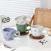 Set of three ceramic cartoon animal coffee mugs in pastel blue sage green and off-white with floral and celestial decorbites 3d cartoon motifs
