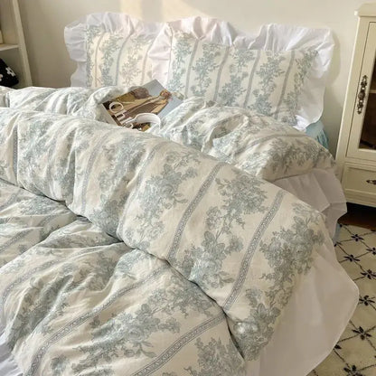 A soft off-white pastel floral korean lace bedding set with delicate light blue patterns and ruffled edges
