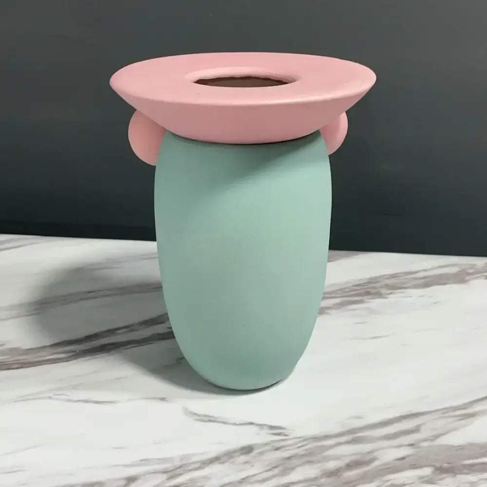 Pastel mint ceramic toothbrush holder with pink flower-shaped lid featured in decorbites geometric ball ceramic vase decor
