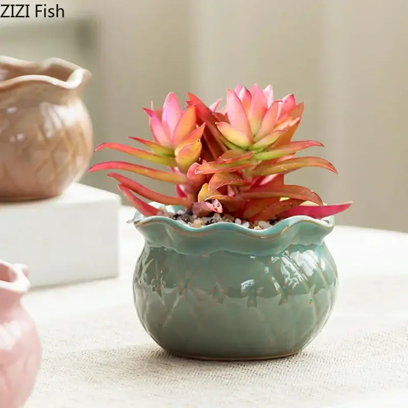 A jade green lotus flower ceramic pot with scalloped rim and embossed leaf pattern holding pink succulents decorbites lotus flower