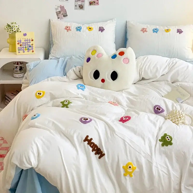 White plush cat-shaped pillow with colorful embroidered eyes on pastel green decorbites cartoon towel bedding set