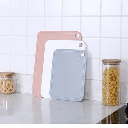 Set of three pastel-colored silicone kitchen cutting boards in pink white and gray with hanging holes from decorbites cutting board set