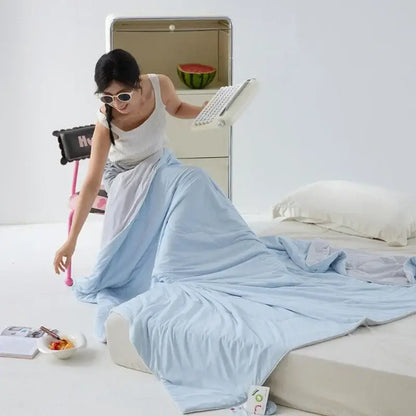 Light blue soft-textured bedsheet draped over a woman showcasing decorbites green summer cooling comforter bedding