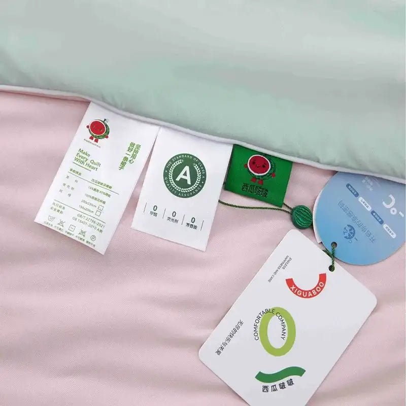 Pink quilt with mint green piping and fabric care tags showing the back side of decorbites green summer cooling comforter