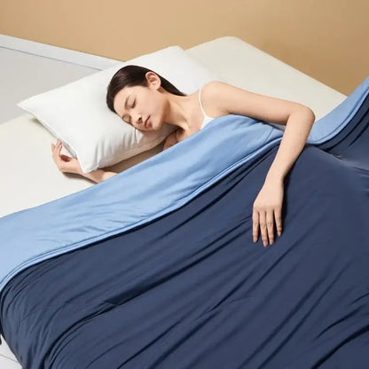 Pastel green summer cooling comforter quilted bedding with soft blue two tone blanket draped over sleeping woman