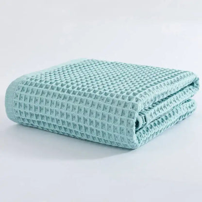 A neatly folded mint green cotton waffle bath towel with a textured grid pattern from decorbites cotton waffle set