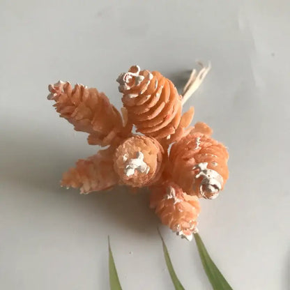 A cluster of orange painted pinecones with silver metallic tips in a pastel pinecone artificial flower wreath for living room decor