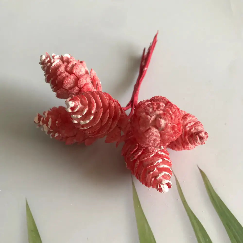 A cluster of vibrant red and white artificial pinecones on thin stems in a pastel artificial flower wreath for living room decor