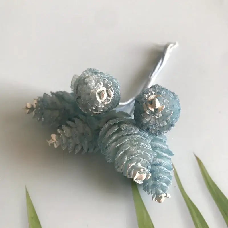 Delicate cluster of frosted blue pinecones with metallic silver accents on wire stem in pastel artificial flower wreath