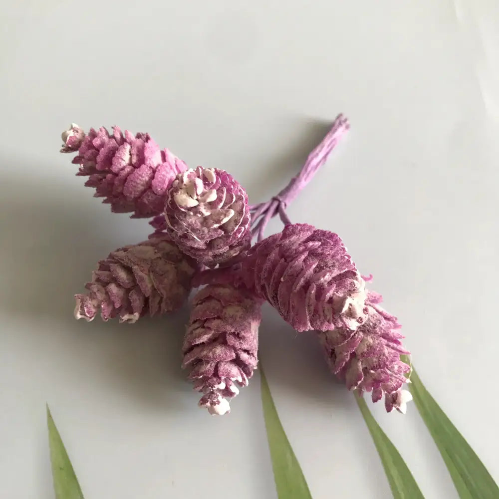 A cluster of dusty rose artificial pinecones with white accents in a pastel artificial flower wreath for living room decor