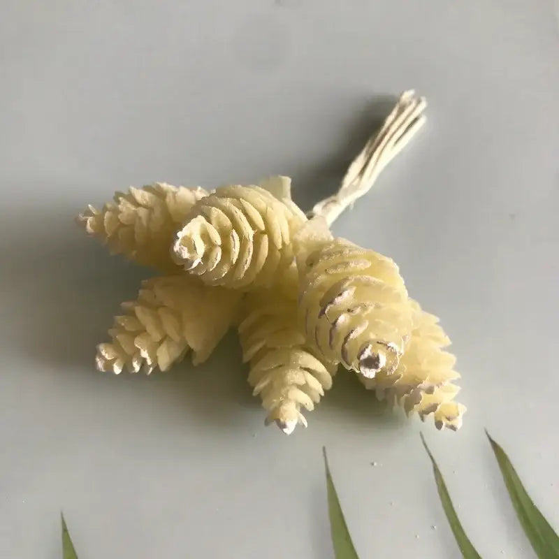 A cluster of pale yellow intricately textured artificial pinecones in a pastel artificial flower wreath for living room decor