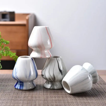 Pastel pink and yellow ceramic matcha whisk stand set with white ceramic vases featuring pink blue and gray marbled patterns