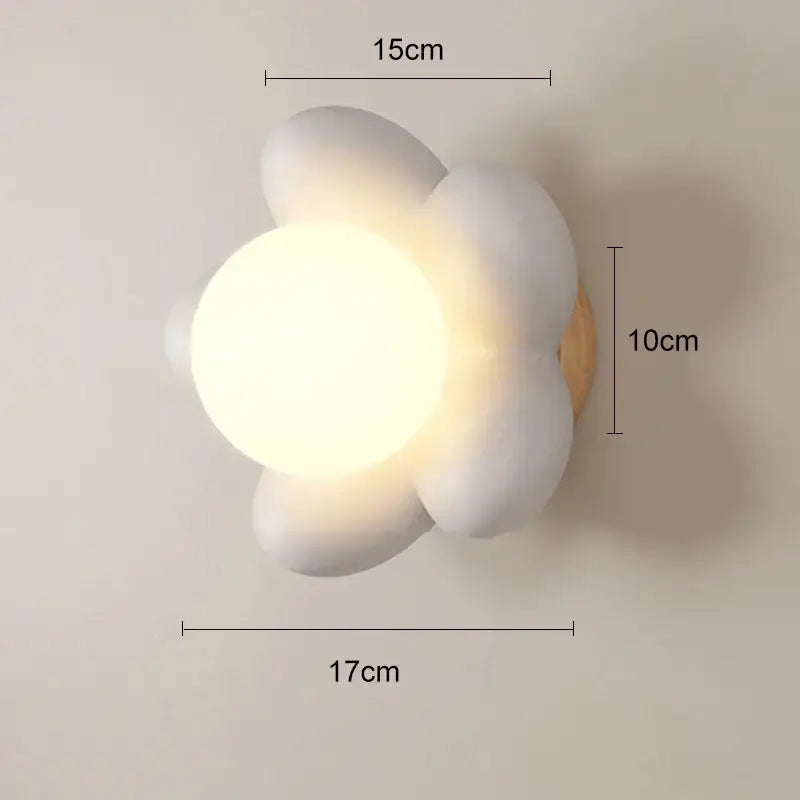 Pastel pink cream flower wall lamp with white ceramic flower design and warm glowing center on wooden base by decorbites cream flower