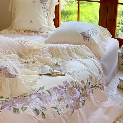 Cream-colored bedding set with delicate pastel pink flowers lace ruffles and soft flowing fabric for bedroom decor