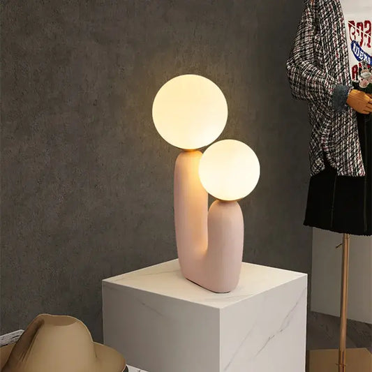 Pastel pink ceramic ball table lamp featuring dual glowing glass ball bulbs for bedroom use