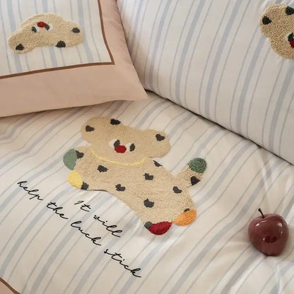 A beige plush teddy bear rug with black spots rests on pastel pink and gray decorbites cotton embroidered bedding set