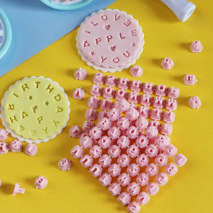 Pastel pink and yellow decorbites cookie stamps set with plastic letter and number molds and circular stamping plates