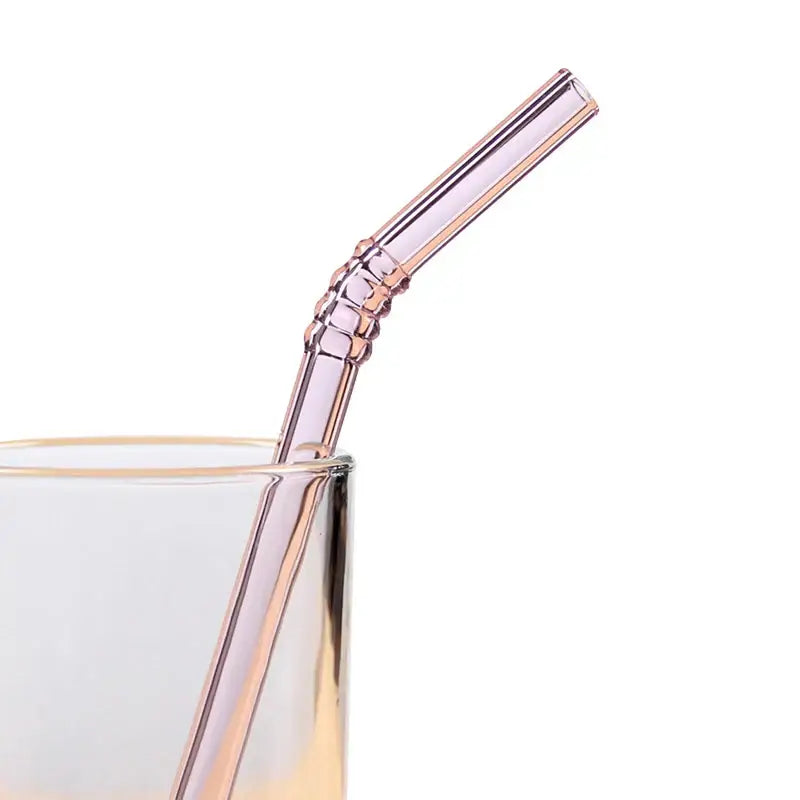 A translucent rose gold glass straw with decorative segmented bend from decorbites glass straws set for eco friendly use
