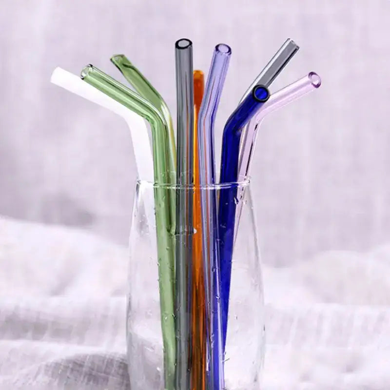 A set of pastel ridged decorbites glass straws in green blue orange and white arranged upright in a clear glass