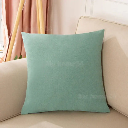A soft teal velvet pillow cover set with textured fabric on a beige sofa for living room decor