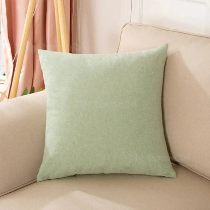 Soft sage green linen-like textured pillow cover resting on beige sofa as part of pastel velvet pillow cover set