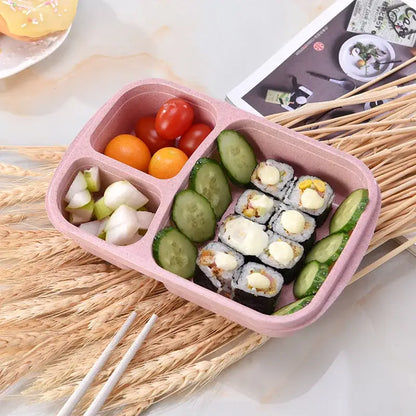 Pastel pink wheat straw bento box set with four compartments filled with sushi and fresh vegetables for lunch use
